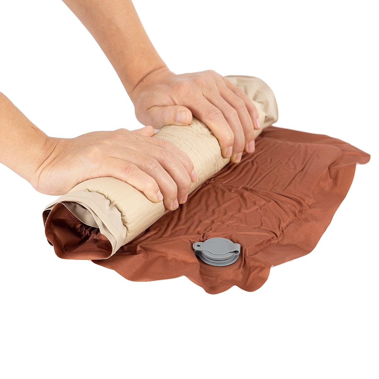 Inflatable pillow being rolled up with hands, showing its self-inflating design and soft material.