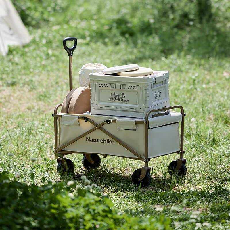 Mini foldable wagon on grass with supplies, four large wheels, 40 kg capacity.