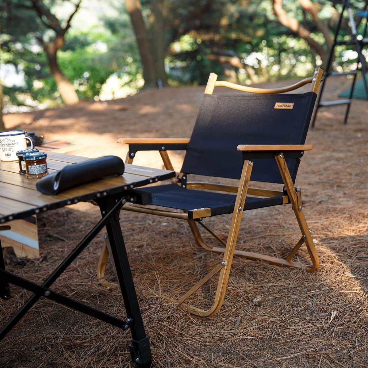 Campingstol i oxford og aluminium ved et udendørs bord i skovmiljø.