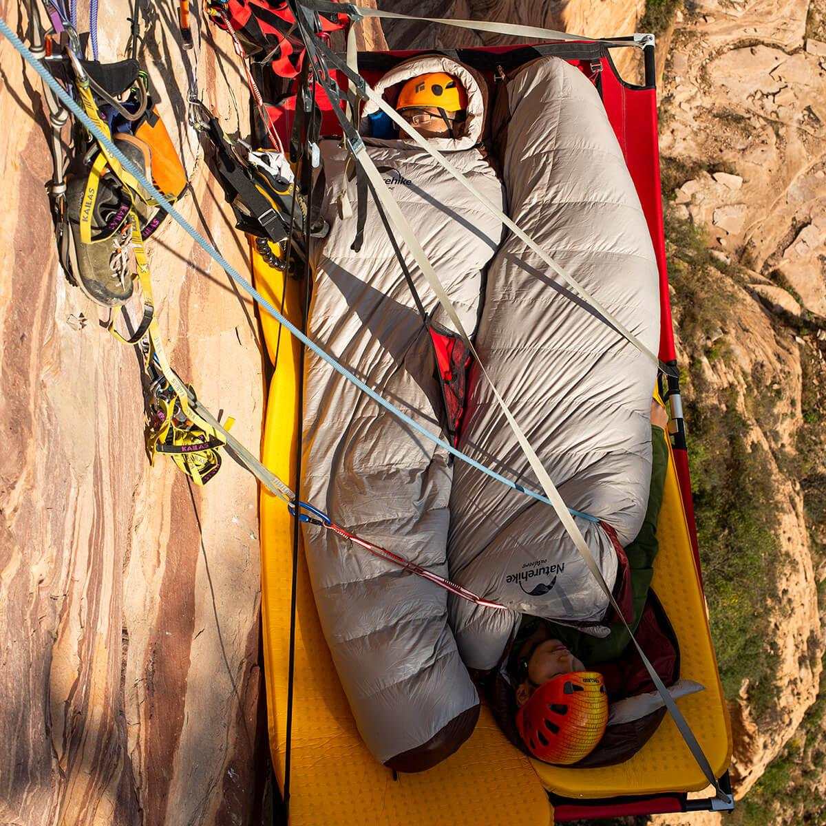 Dunsovepose mummy / 0° sleeping bag in use during a rock climbing expedition, featuring durable nylon and down insulation.